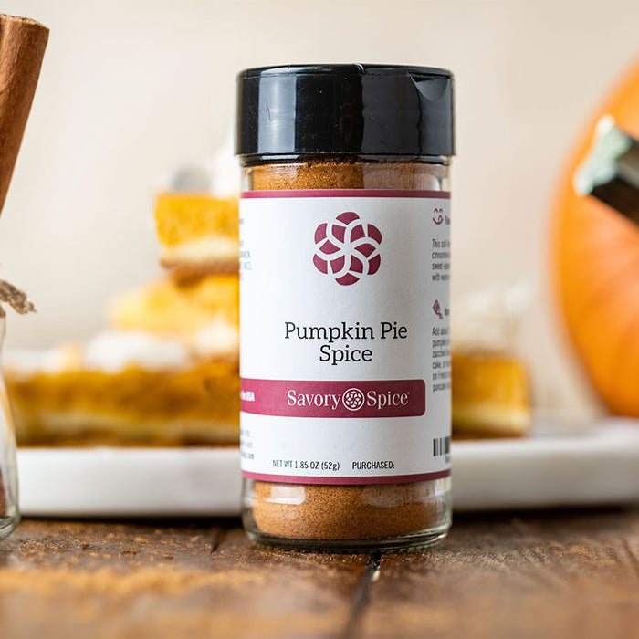 A bundle of cinnamon sticks, a jar of Pumpkin Pie Spice, a pumpkin (left to right)
