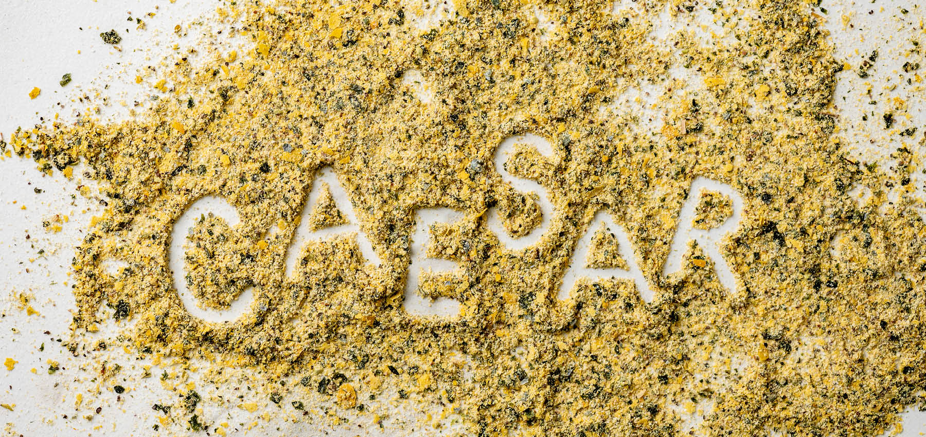The word Caesar written inside a spill of Caesar Seasoning