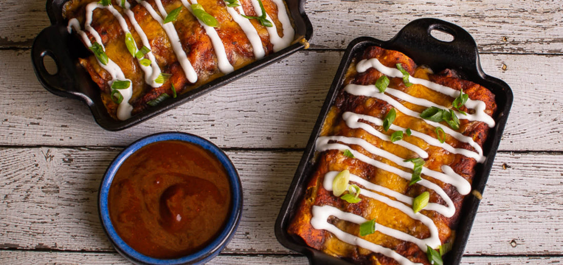 Two pans of enchiladas with a bowl of sauce