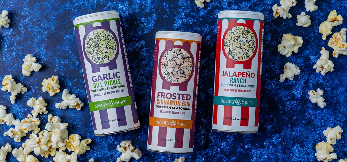 Garlic Dill Pickle, Frosted Cinnamon Bun, Jalapeno Ranch Popcorn Seasonings on a blue background with popcorn