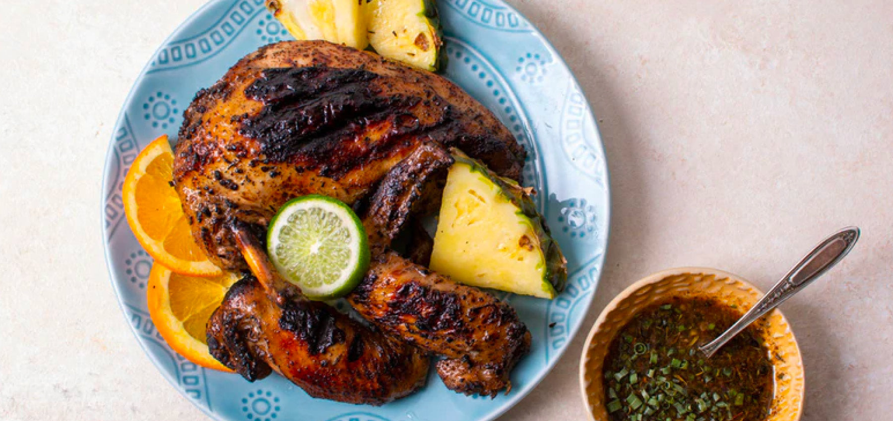 Grilled jerk chicken on plate with fruit garnishes