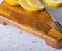 Wooden cutting board with lemon slices and a knife on top. 