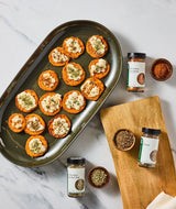 Tray of sweet potato rounds with various seasonings on a marble surface