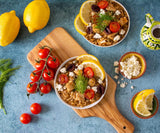 Overhead shot of two finished bowls of Mediterranean Dill Risotto garnished with feta cheese, tomatoes, and lemon
